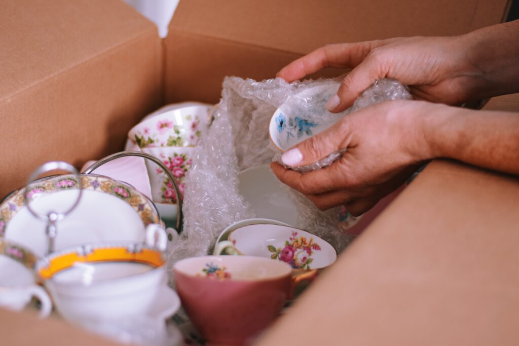 La mujer está empacando platos de porcelana fina en una caja de cartón para moverse