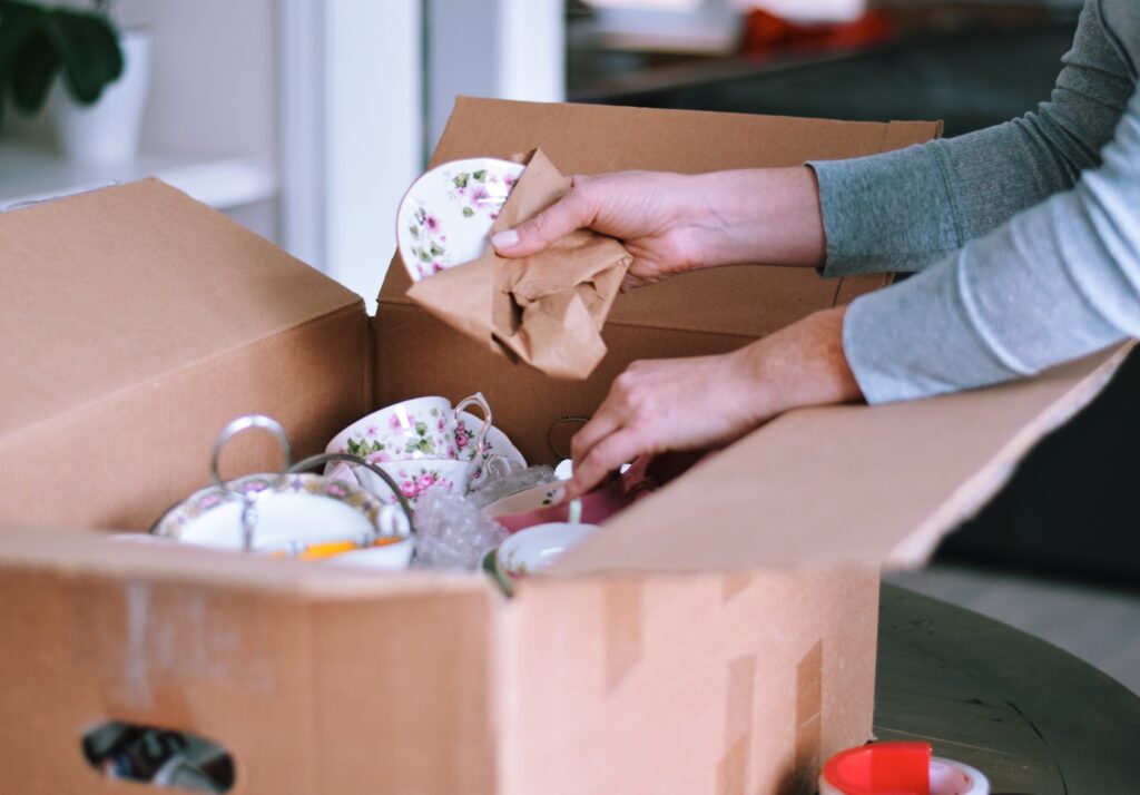 Mujer empacando platos de porcelana fina en una caja de cartón para mudarse